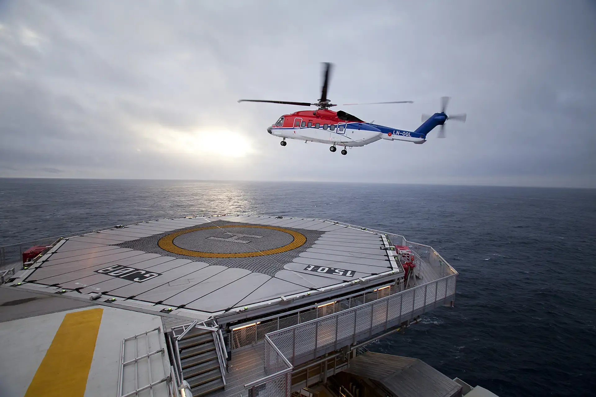 A helicopter coming in over an offshore helideck at sea
